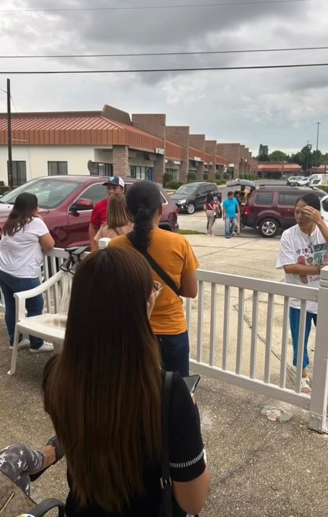 Neighbors waiting along the white railing outside before the food distribution opens